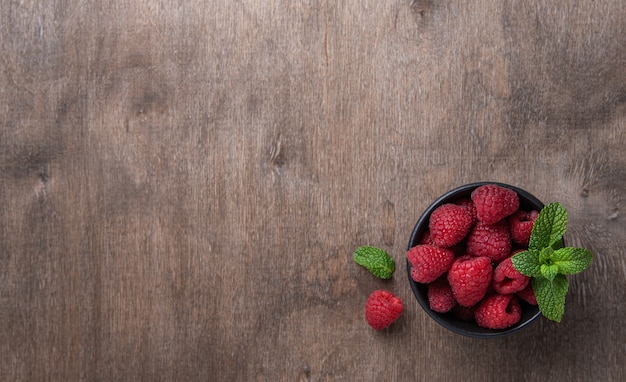 Fresh raspberry with mint in  bowl on old vintage wood background