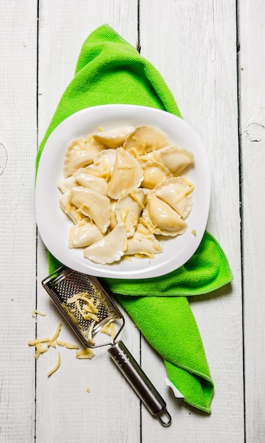 Fresh ravioli with cheese in the plate. On a white wooden table. Top view