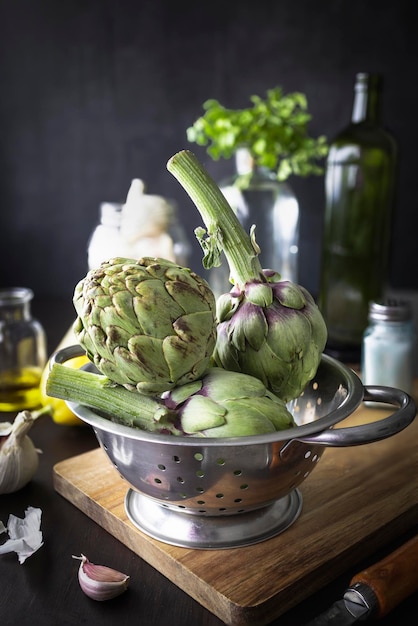 Fresh and raw artichokes on the kitchen table and with a dark background