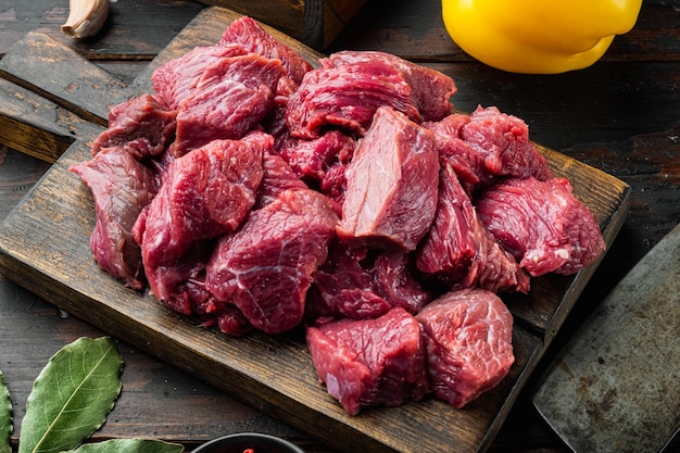 Fresh raw beef cubes set with sweet bell pepper on old dark wooden table