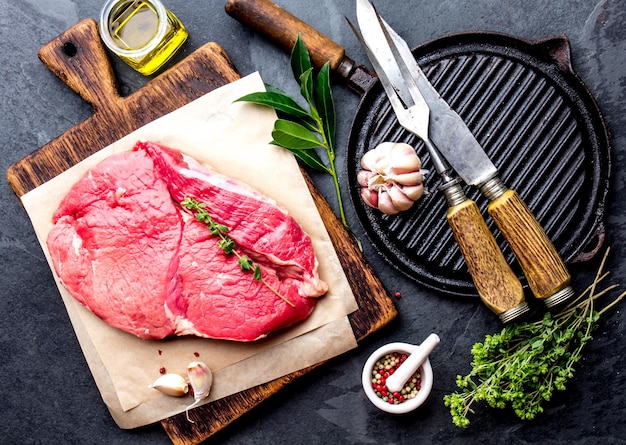 新鮮な生の牛肉肉ビーフ テンダーロイン調味料ハーブ スパイスと木の板黒背景トップ ビューにオイル