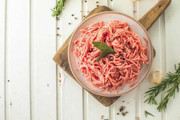 写真 新鮮な生の牛ひき肉とハーブとローズマリーを木の板に明るい背景のバナーメニューレシピの場所にテキストトップビュー