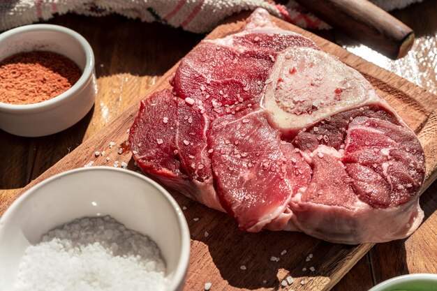 나무 테이블에 장식이 있는 보드에 있는 신선한 생 쇠고기 오소부코 스테이크 동물성 단백질 개념 이탈리아 음식 에어리얼 전망