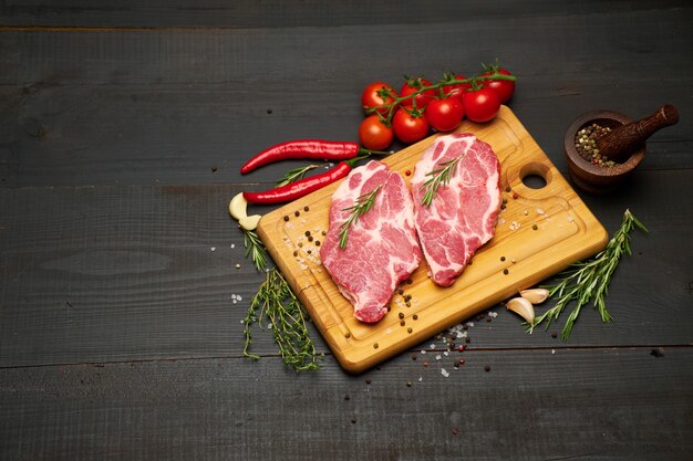 Fresh raw beef or pork steaks on wooden cutting board