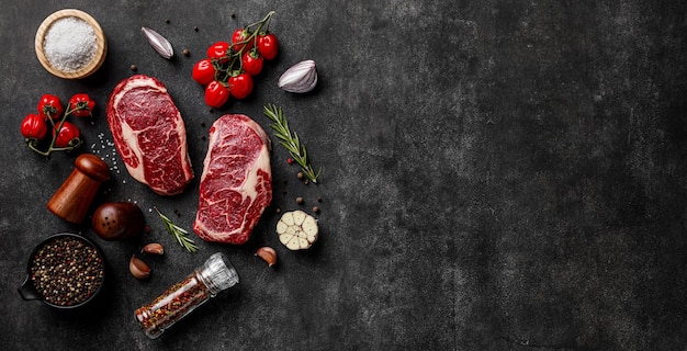 Photo fresh raw beef ribeye steak with spices on stone board
