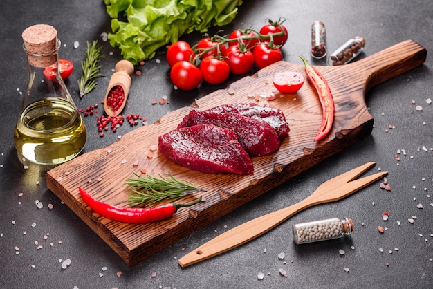 Fresh Raw Beef steak Mignon, with salt, peppercorns, thyme, tomatoes. Raw fresh marbled meat Steak and seasonings