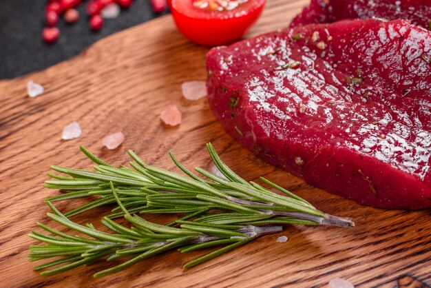 Fresh Raw Beef steak Mignon, with salt, peppercorns, thyme, tomatoes. Raw fresh marbled meat Steak and seasonings