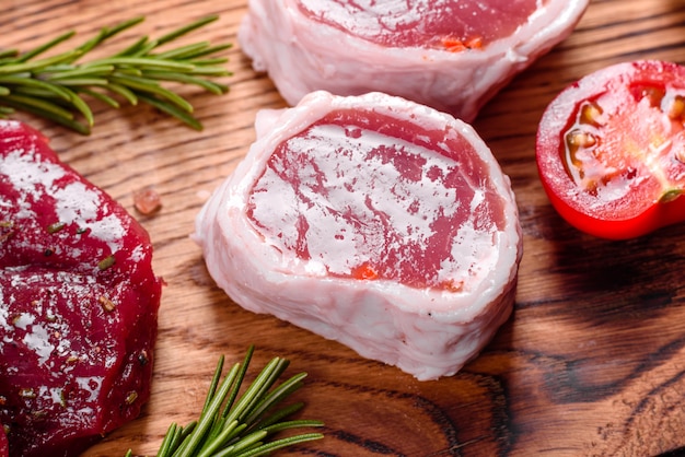Fresh Raw Beef steak Mignon, with salt, peppercorns, thyme, tomatoes. Raw fresh marbled meat Steak and seasonings