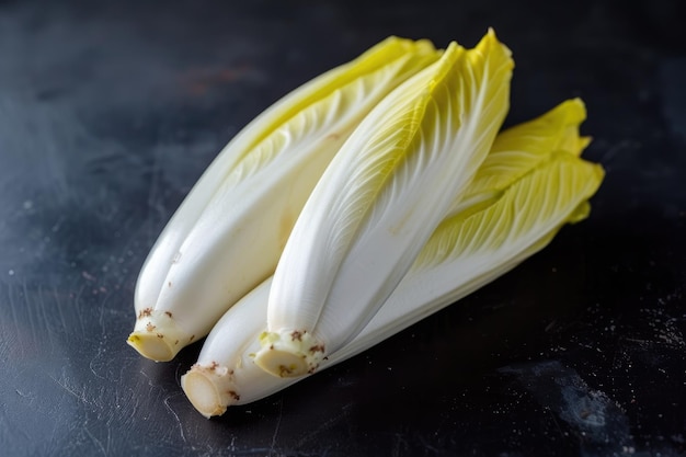 Photo fresh raw belgian endives chicory on black table closeup