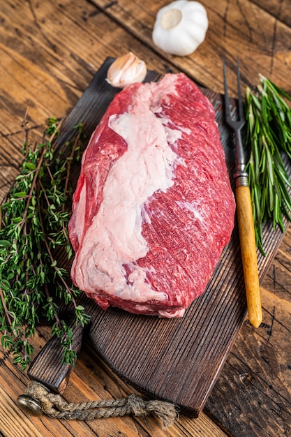 Fresh Raw brisket beef meat prime cut on a wooden  board with herbs. wooden background. Top view.