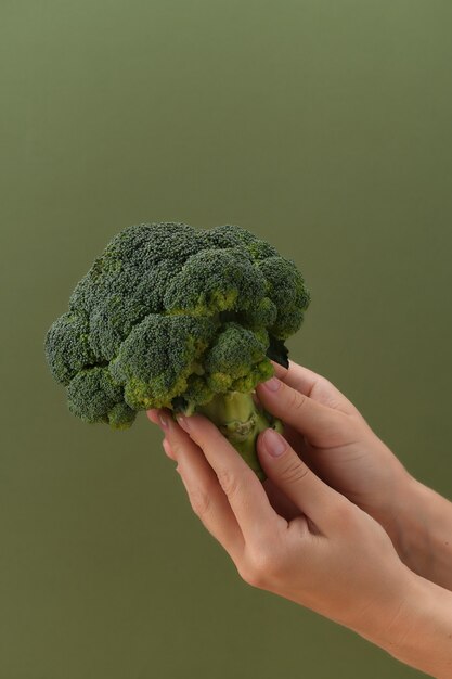 Fresh raw broccoli in hand healthy eating and vegetarianism concept