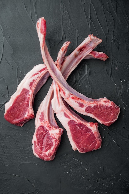 Fresh raw butchers lamb beef cutlets set, on black stone table, top view flat lay