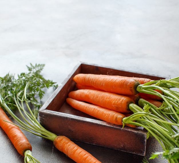 Fresh raw carrots with leaves on a wooden table