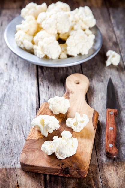 Fresh raw cauliflower on cutting board on a wooden table