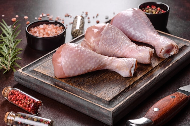 커팅 보드에 향신료, 소금, 허브를 넣은 신선한 생 닭 다리. 오븐에서 굽기 위한 요리 준비