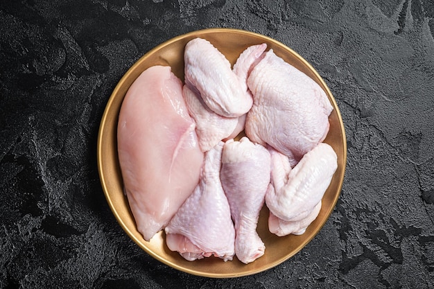 Fresh raw chicken meat with various parts  drumstick breast fillet wings thigh Black background Top view