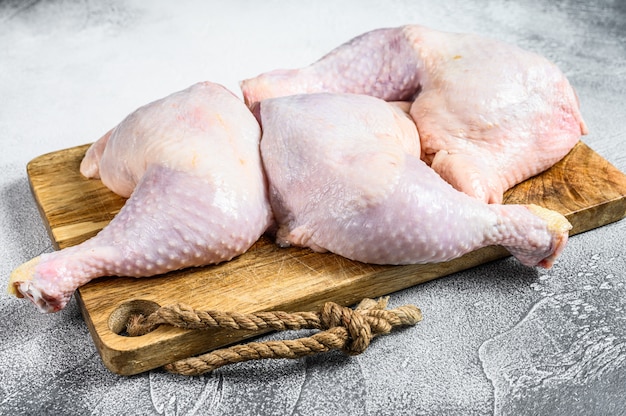 Fresh raw chicken thighs, legs on a chopping Board. Gray background. .