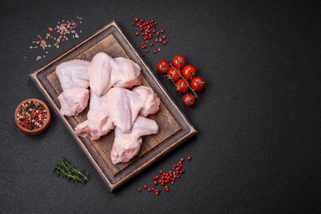 Fresh raw chicken wings with salt and spices prepared for baking on a dark concrete background