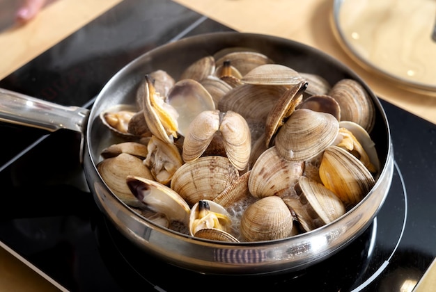 Fresh raw clams lie in a skillet on an electric stove Cooking delicious food 45 view