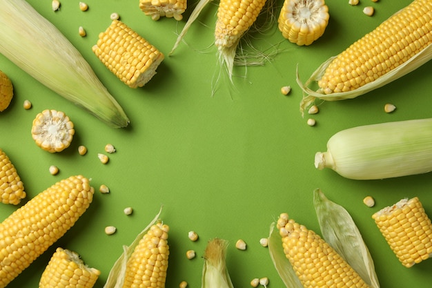 Fresh raw corn on green background, top view