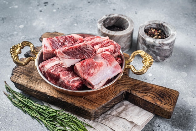 Fresh Raw diced beef marbled meat in steel skillet with herbs ready for cooking Gray background Top view