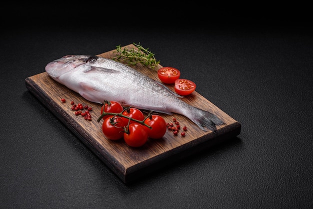 Fresh raw dorada fish with salt spices and herbs on a dark concrete background