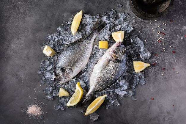 Свежая сырая рыба дорадо со специями, лимон, перец, петрушка
