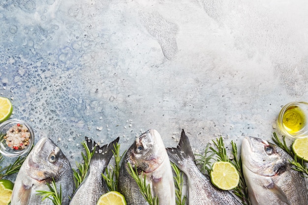 Fresh raw Dorado or sea bream with spices, herbs, lemon and salt over blue background Top view