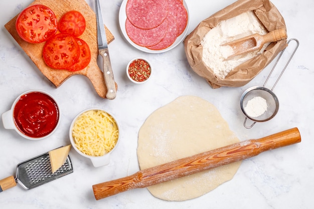 Fresh raw dough, flour and pizza ingredients