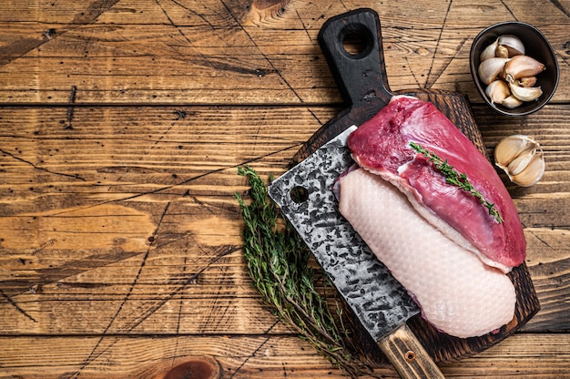 Фото Свежие сырые стейки из филе утиной грудки на мясной доске с ножом для мяса
