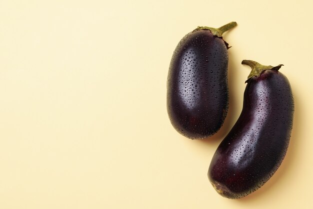 Fresh raw eggplants with water drops on beige 