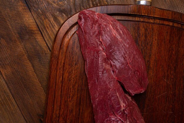 Photo fresh and raw filet mignon on wooden board with horn handle wooden table in the background