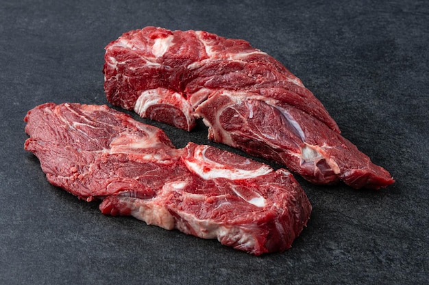 Свежее и сырое мясо филе Целый кусок стейков из говяжьей вырезки на фоне черного каменного стола без украшения