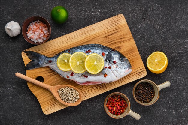 Fresh raw fish with spices on wooden board