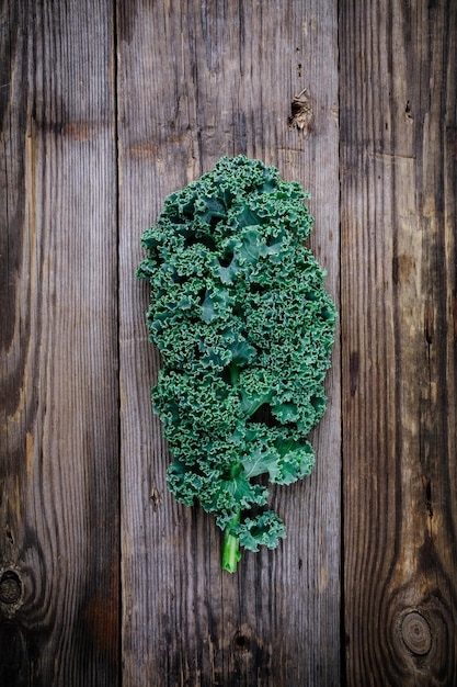 Fresh raw green superfood kale curly cabbage leaves on wooden background