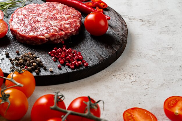 Fresh raw home-made cutlet with spices and tomatoes on the table