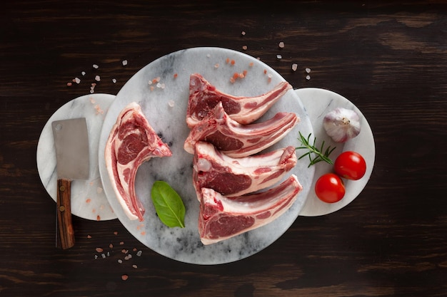 Fresh raw lamb on ribs on  stone marble kitchen board on dark wooden background