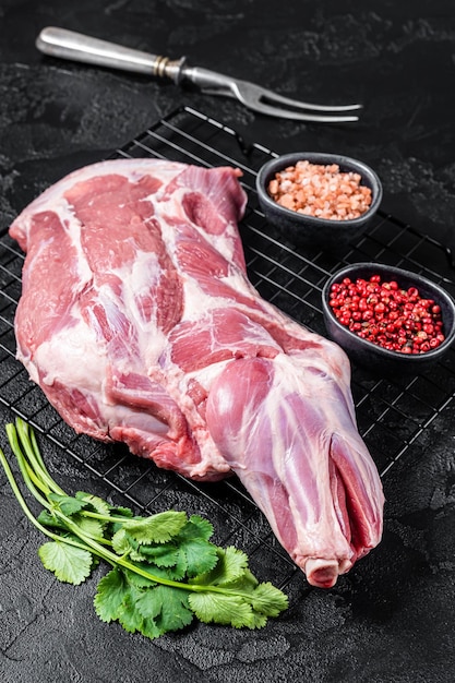 Fresh Raw lamb shoulder leg on kitchen table ready for cooking Black background Top view