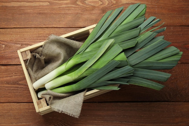 Fresh raw leeks in crate on wooden table top view