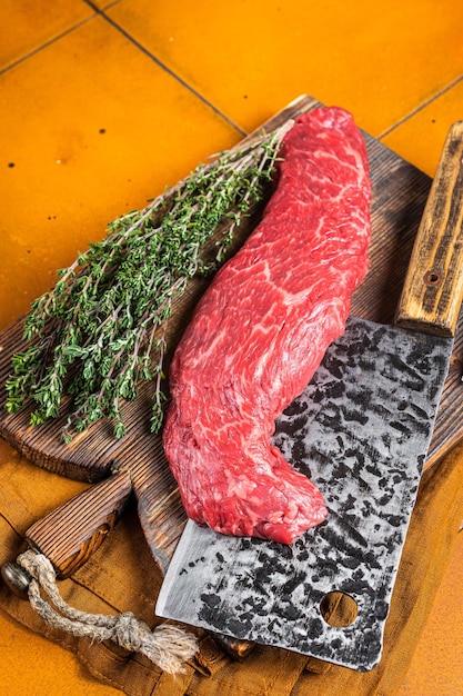 Fresh Raw Machete beef meat steak or hanging tender cut on butcher cutting board Orange background Top view