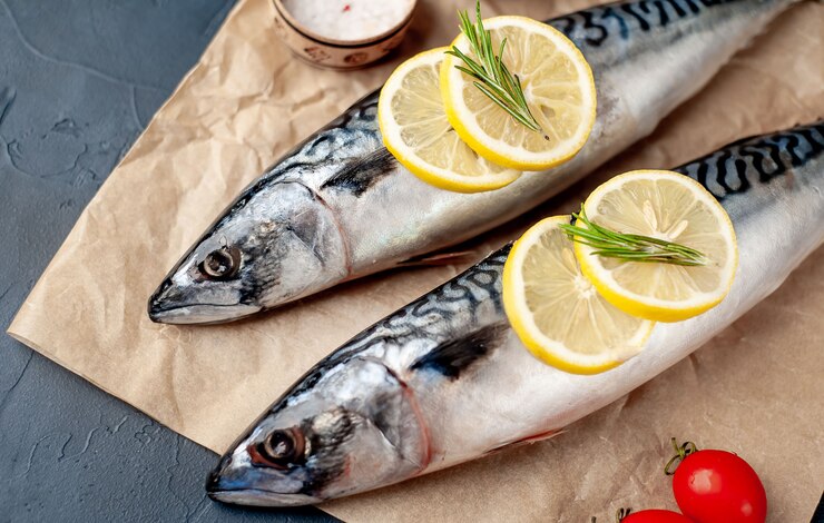 Свежая, сырая скумбрия со специями, помидорами, розмарином на каменном фоне
