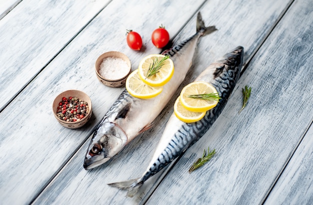 Fresh, raw mackerel with spices, tomatoes, rosemary on a wood background