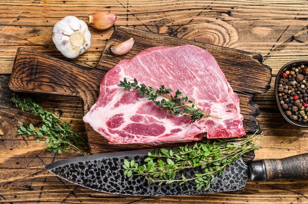 Fresh Raw marble meat pork steaks on a cutting board with knife