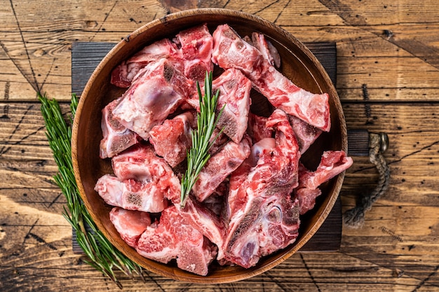 Carne cruda fresca sull'osso tagliata a dadini per gulasch in un piatto di legno. fondo in legno. vista dall'alto.