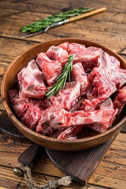 Fresh Raw meat on the bone diced for goulash in a wooden plate. Wooden background. Top View.