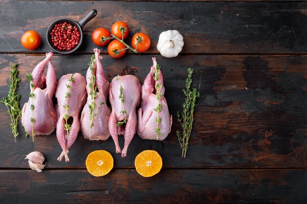 Fresh raw meat quails with herbs, flat lay, on dark wooden background  with space for text