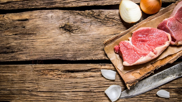 Carne cruda fresca con un coltello da macellaio e una cipolla.