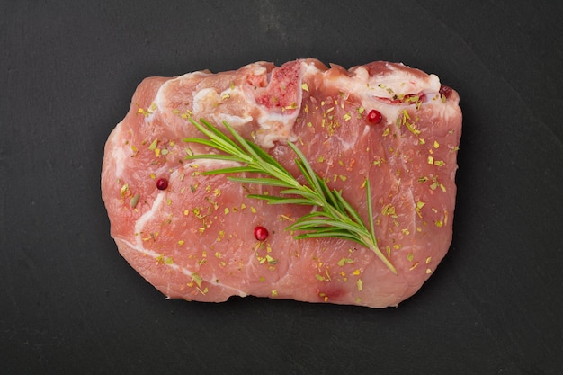 Fresh Raw Meat with rosemary and other Spices on gray stone plate.