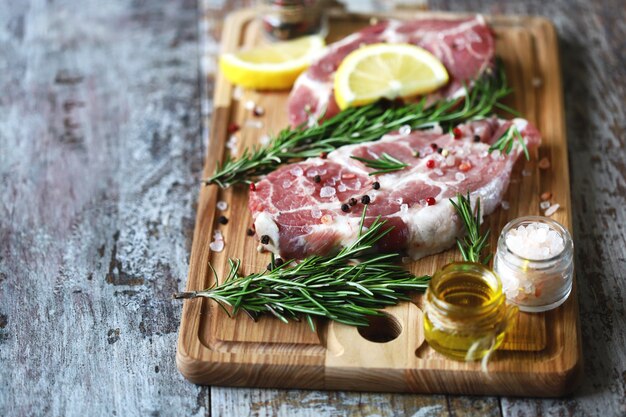 Fresh raw meat with rosemary and spices on a wooden board