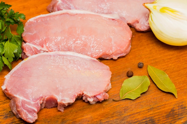 Fresh raw meat with spices on wooden background